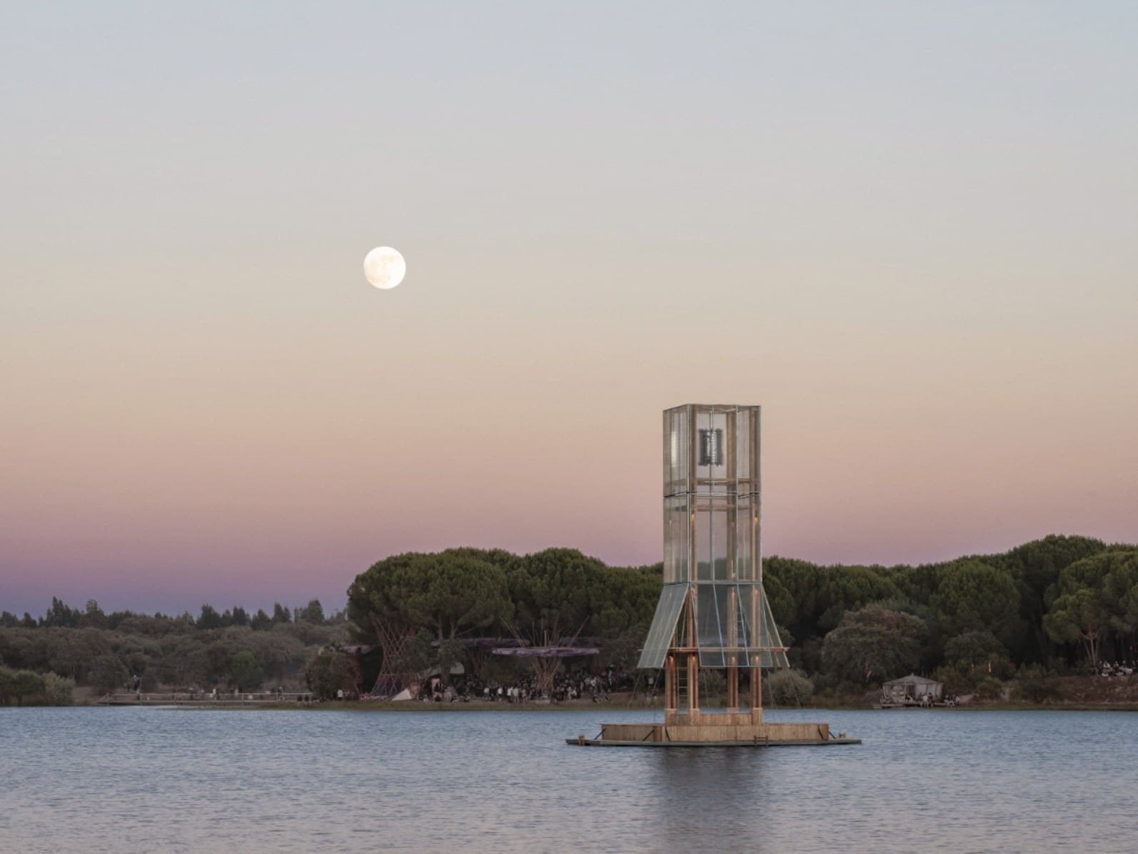 The tower at moonrise, a full moon above it and a crowd gathered along the far shore