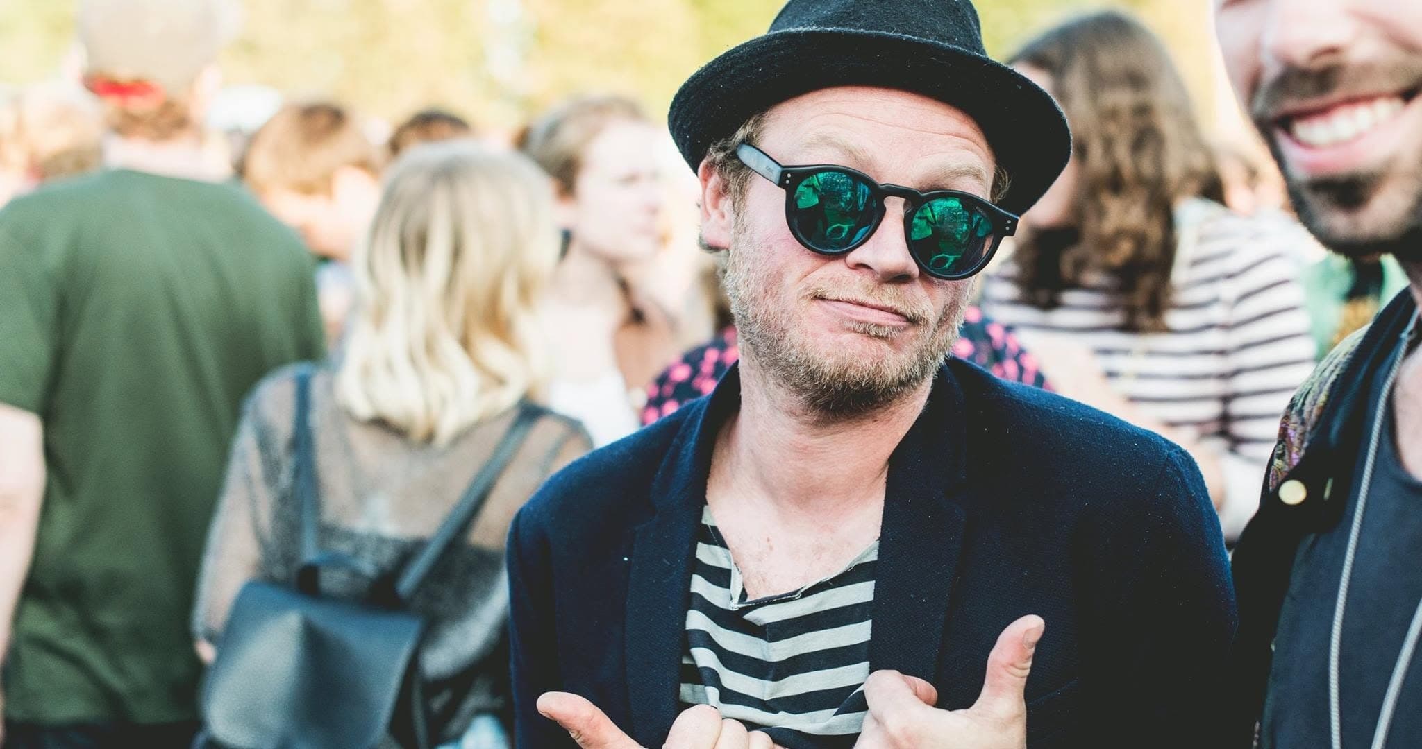 Djuppe at the workshop, hat and sunglasses, giving a shaka sign